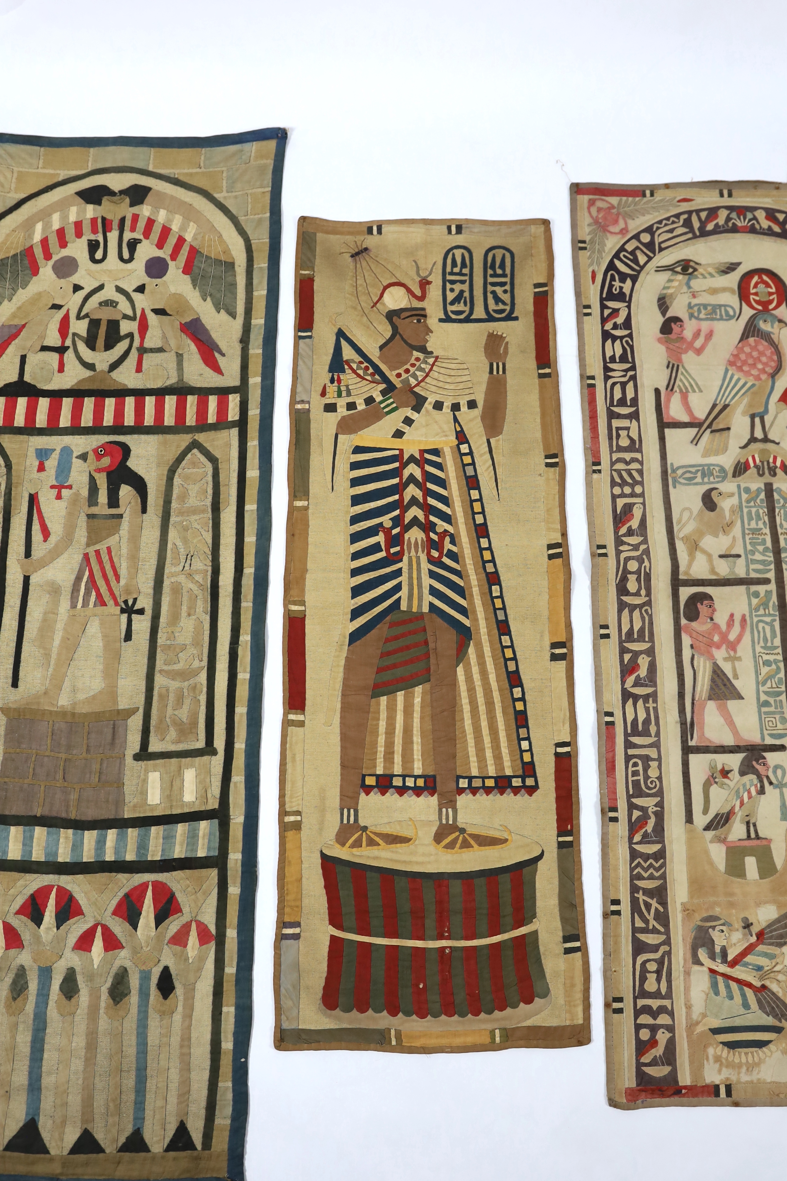 Four 1930’s Egyptian appliqué wall panels, (a pair and two single panels), decorated with various hieroglyphs, Gods and Pharaohs, the panels made for the European market experiencing an Egyptian revival after the discove